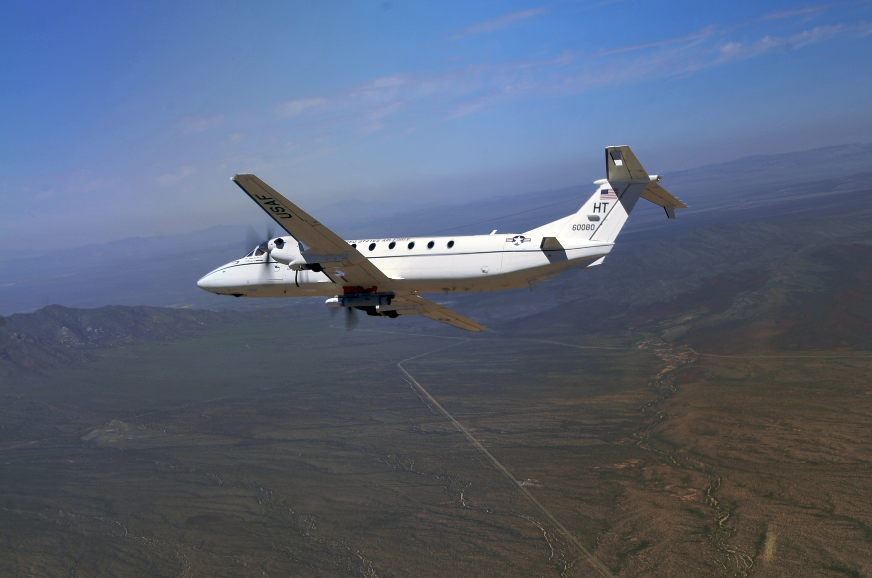 Un C-12J dell'Aeronautica fortemente modificato, con un missile Laser Maverick inerte sotto la pancia della fusoliera, in volo dopo una missione di prova il 26 agosto 2010