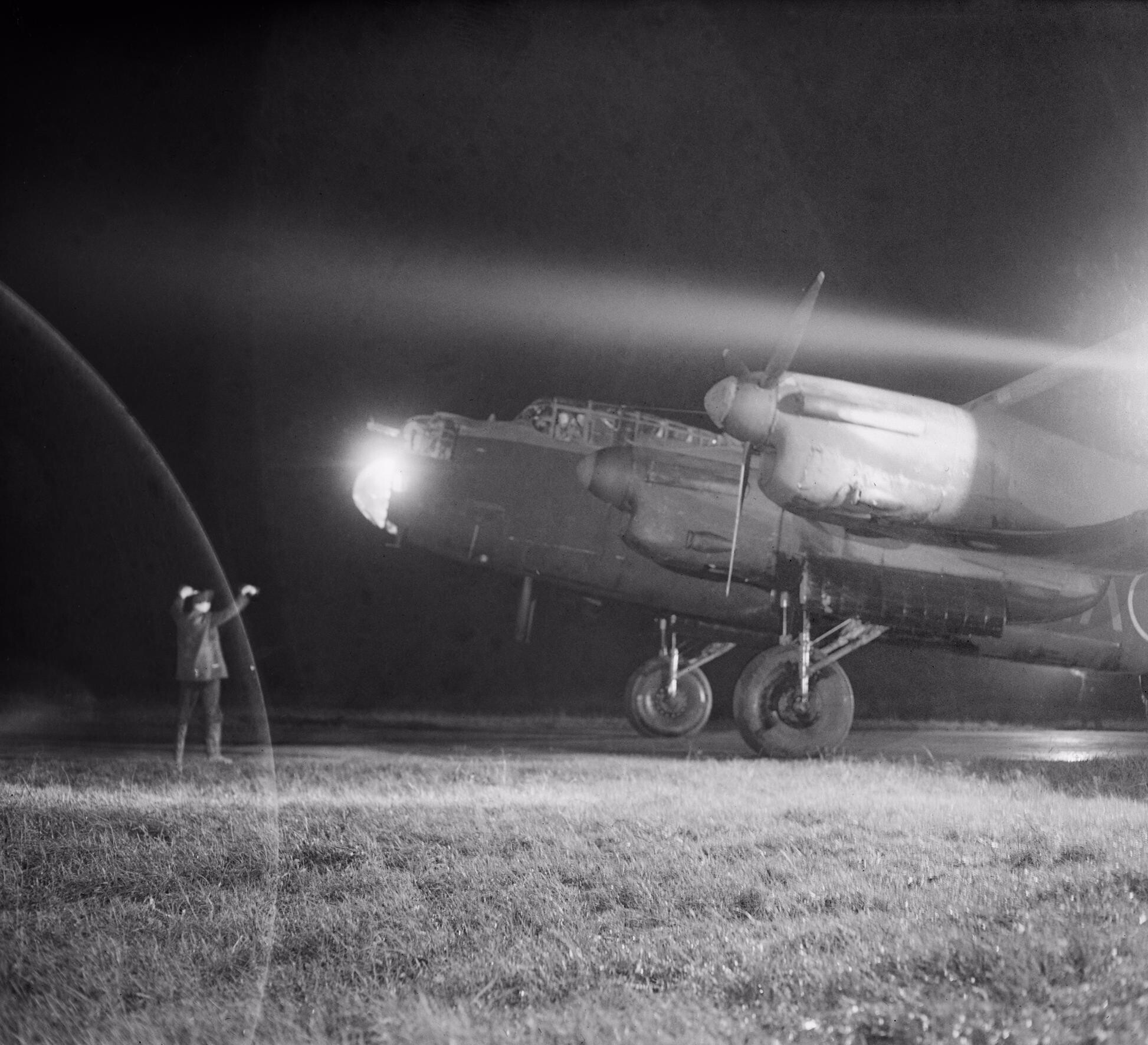 Personal de tierra guiando un Lancaster Mk III del Escuadrón 49 a su dispersión en Fiskerton tras una incursión sobre Berlín
