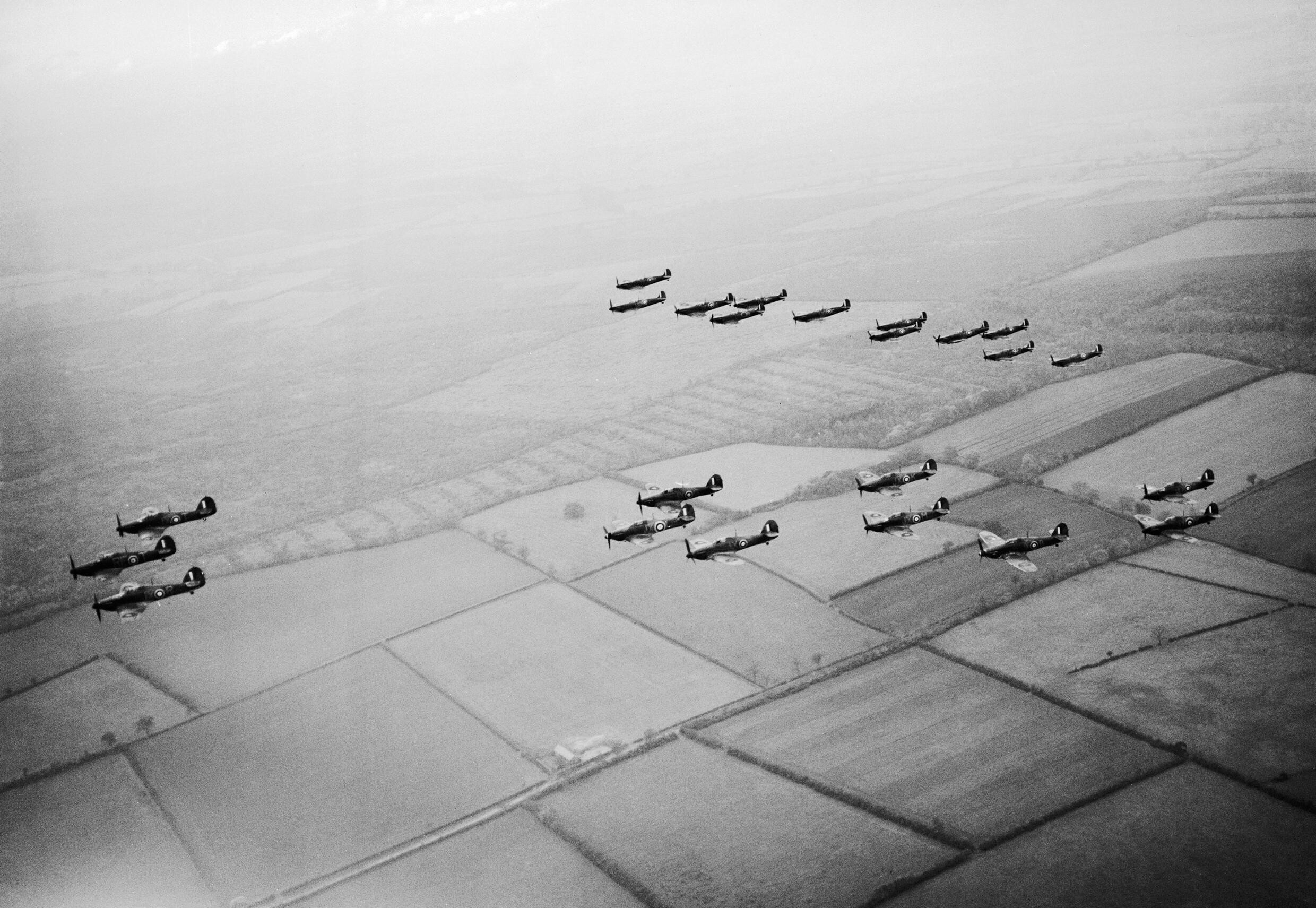 Hawker Hurricanes of No 1 Squadron, Royal Air Force, based at Wittering, Cambridgeshire, followed by a similar formation of Supermarine Spitfires of No 266 Squadron, during a flying display for aircraft factory workers, CH1561