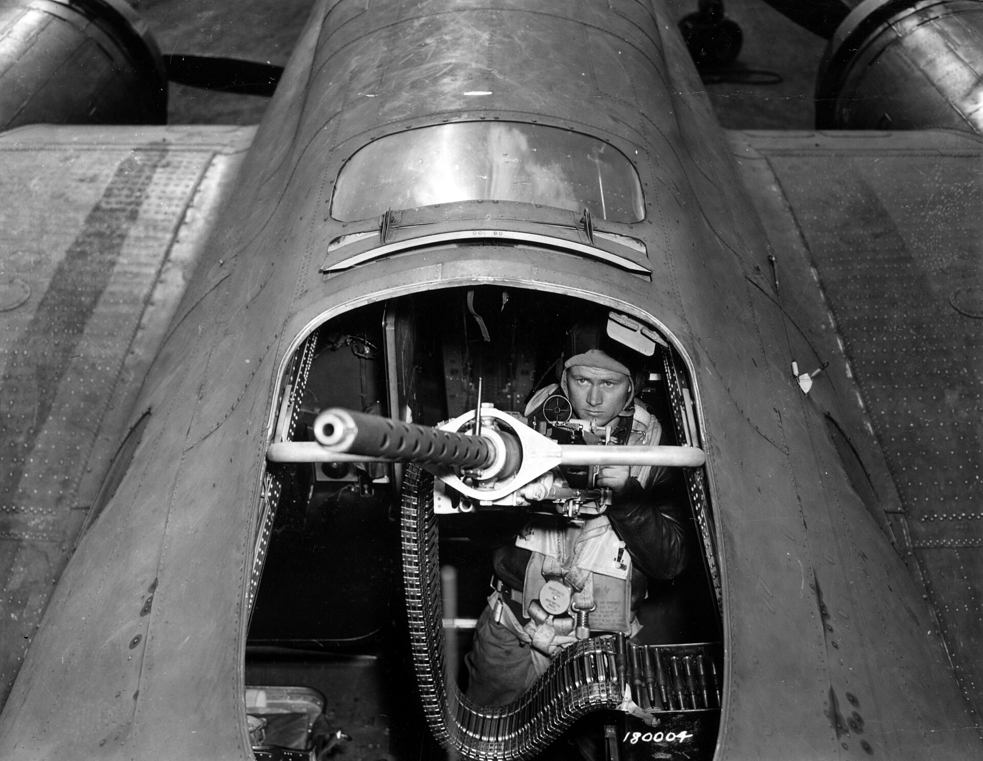 SC 180003 - T Sgt. Arthur L. Smith, Norwich, Kansas, radio gunner of "Our Gang", a Flying Fortress operating from England, takes a final look over one of the ship's guns before she takes off on another mission