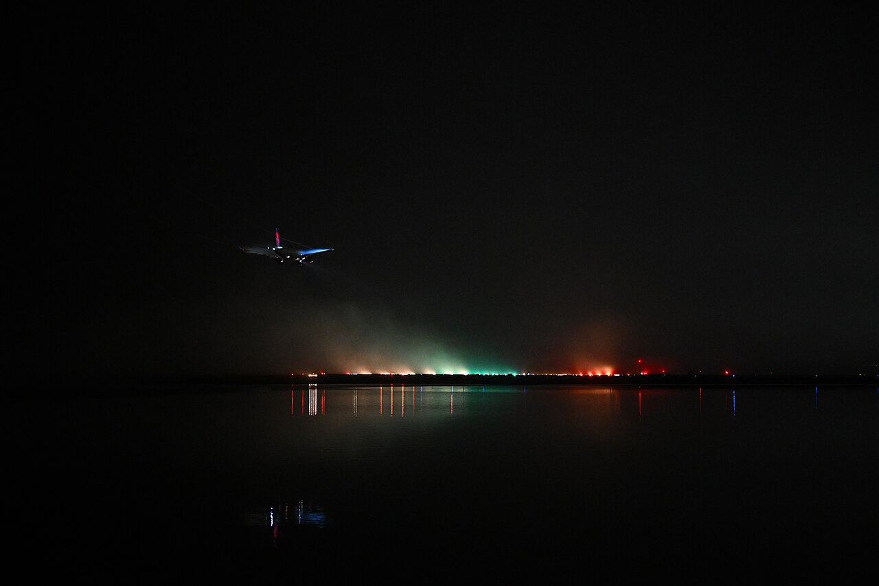 Airliner landing through dense fog above the runway lights.