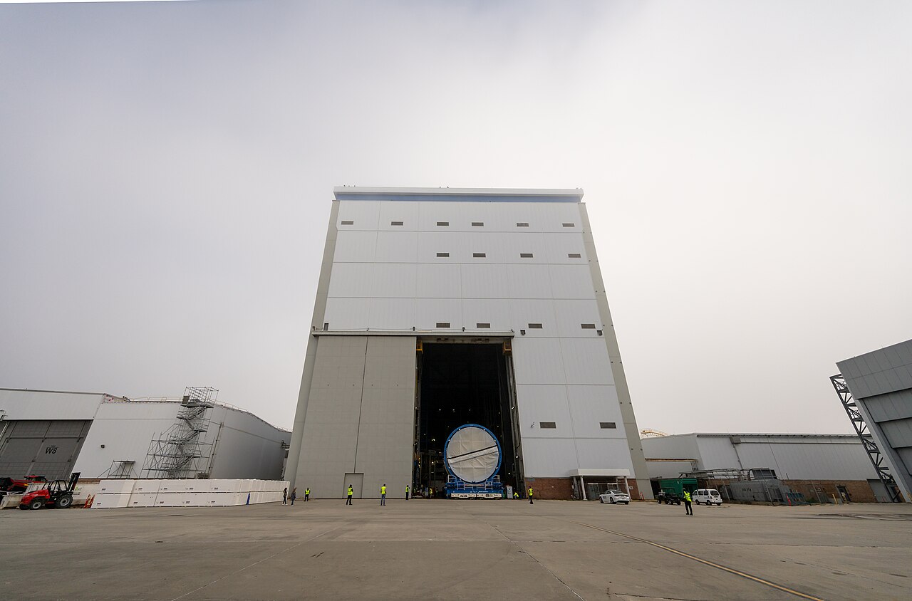 A large rocket section emerging through the door of the vertical assembly building.