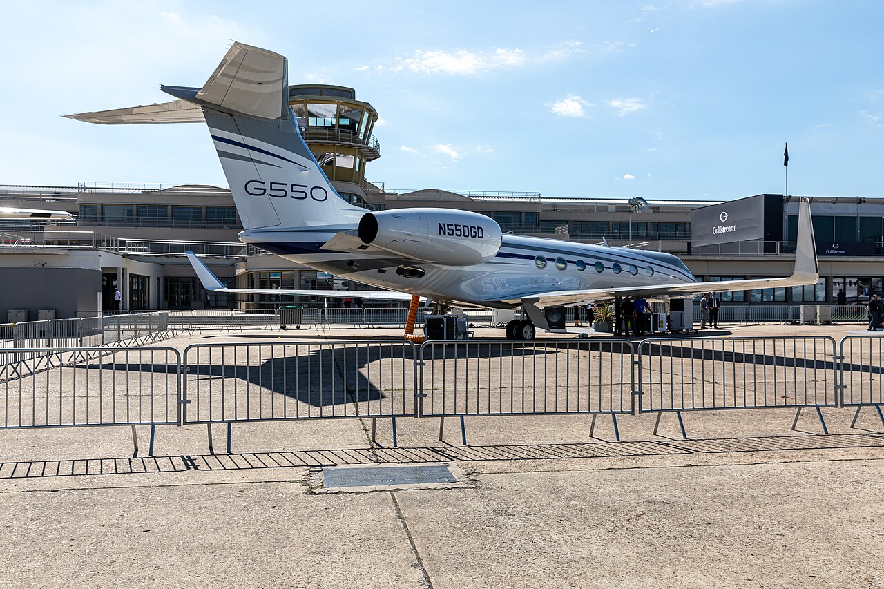 Business jet displayed in front of a manufacturer's pavilion at an air show.