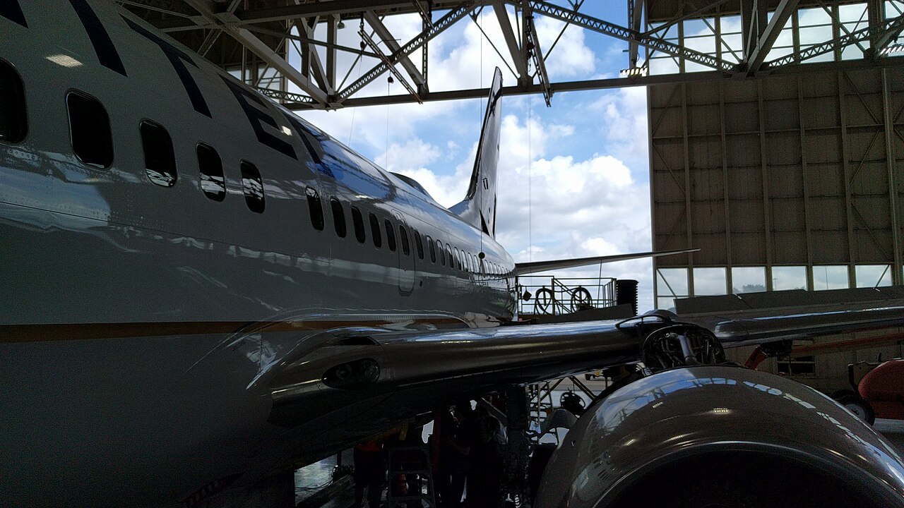 Airliner undergoing maintenance inside an airline hangar.
