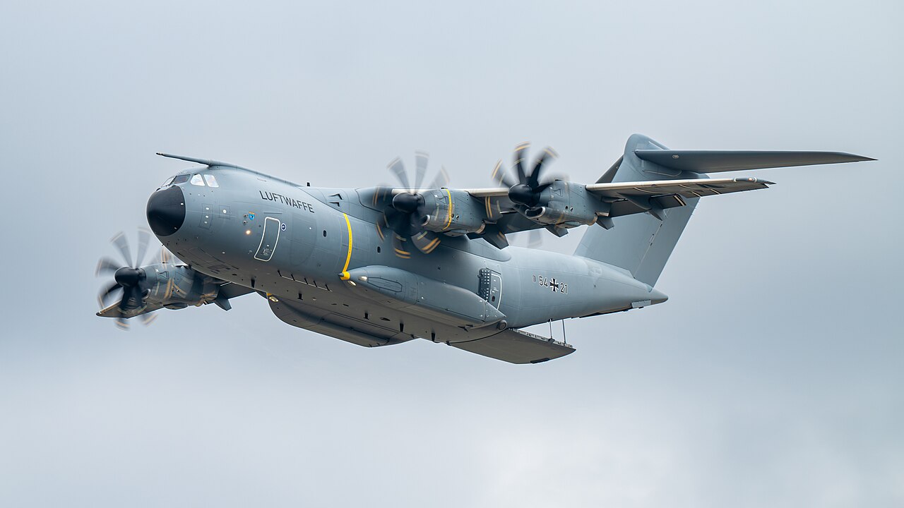 An Airbus A400M military transport aircraft flies with its cargo ramp open.