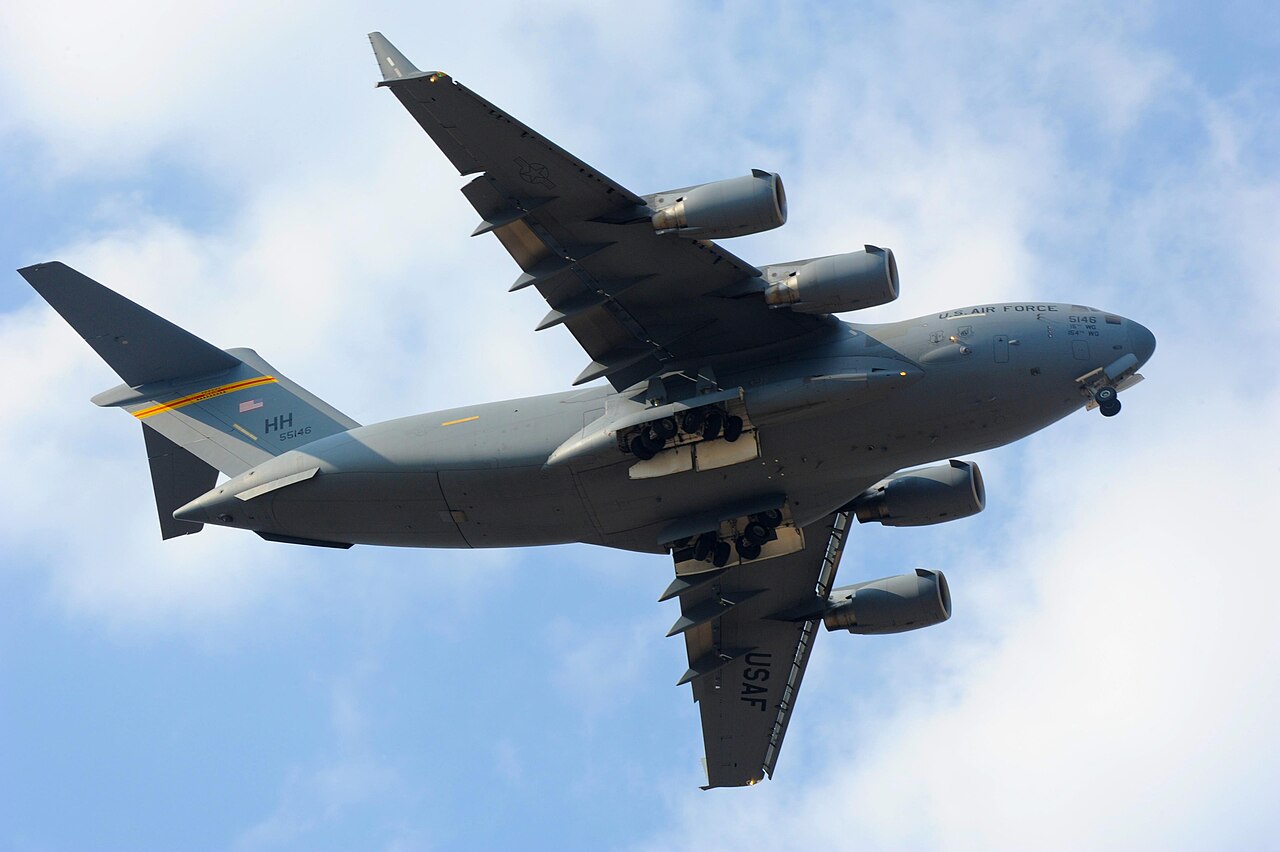 A C-17 Globemaster III transport aircraft in flight with its landing gear extended.