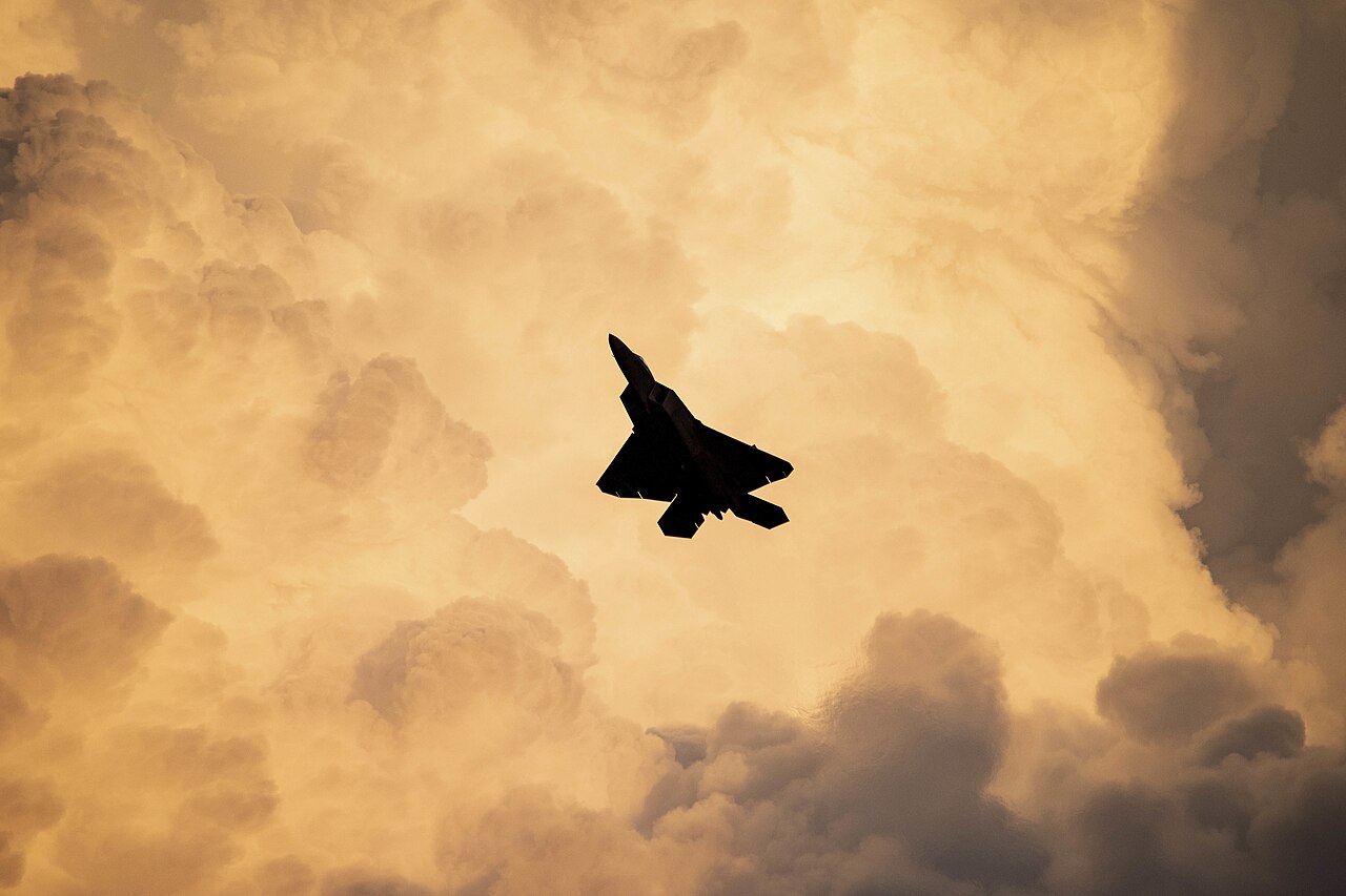 An F-22 Raptor stealth fighter in flight at twilight.