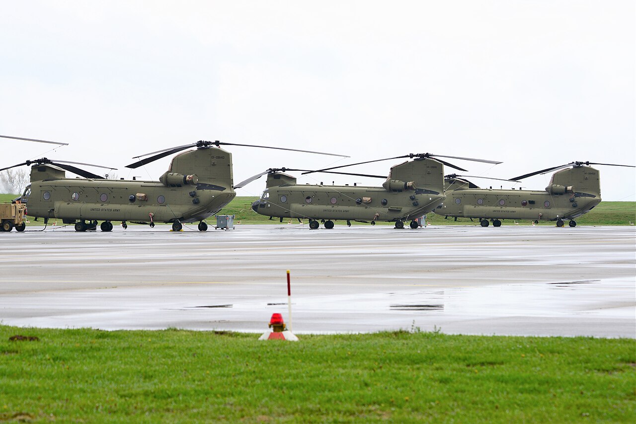 CH-47 Chinook transport helicopters parked on the apron of a military airfield.