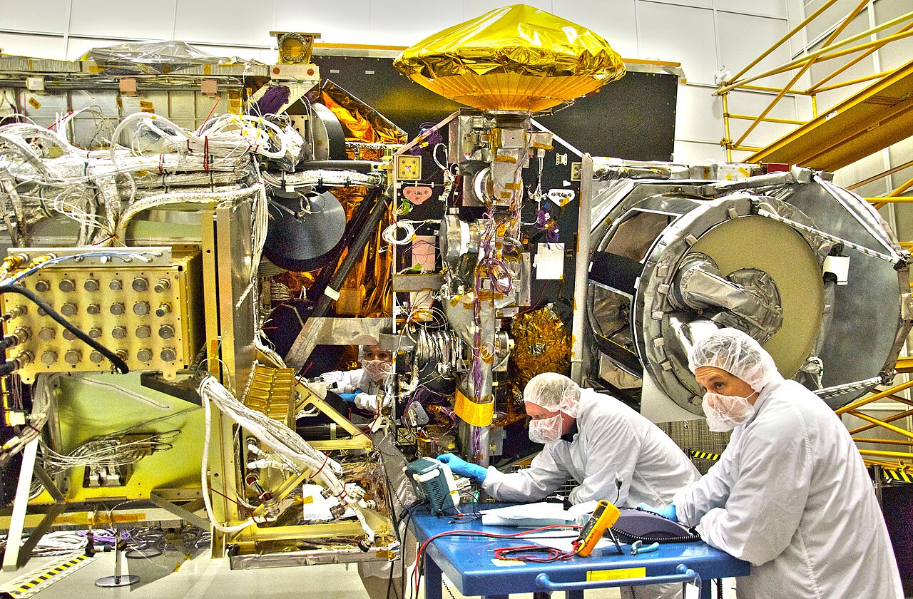 Engineers work on a satellite inside a clean room at NASA's Goddard Space Flight Center.