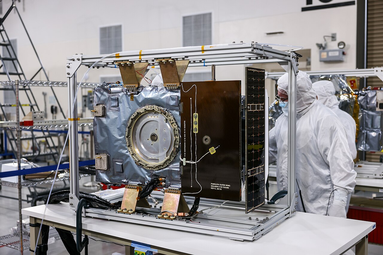 Technicians run a solar array deployment test on a NASA satellite.