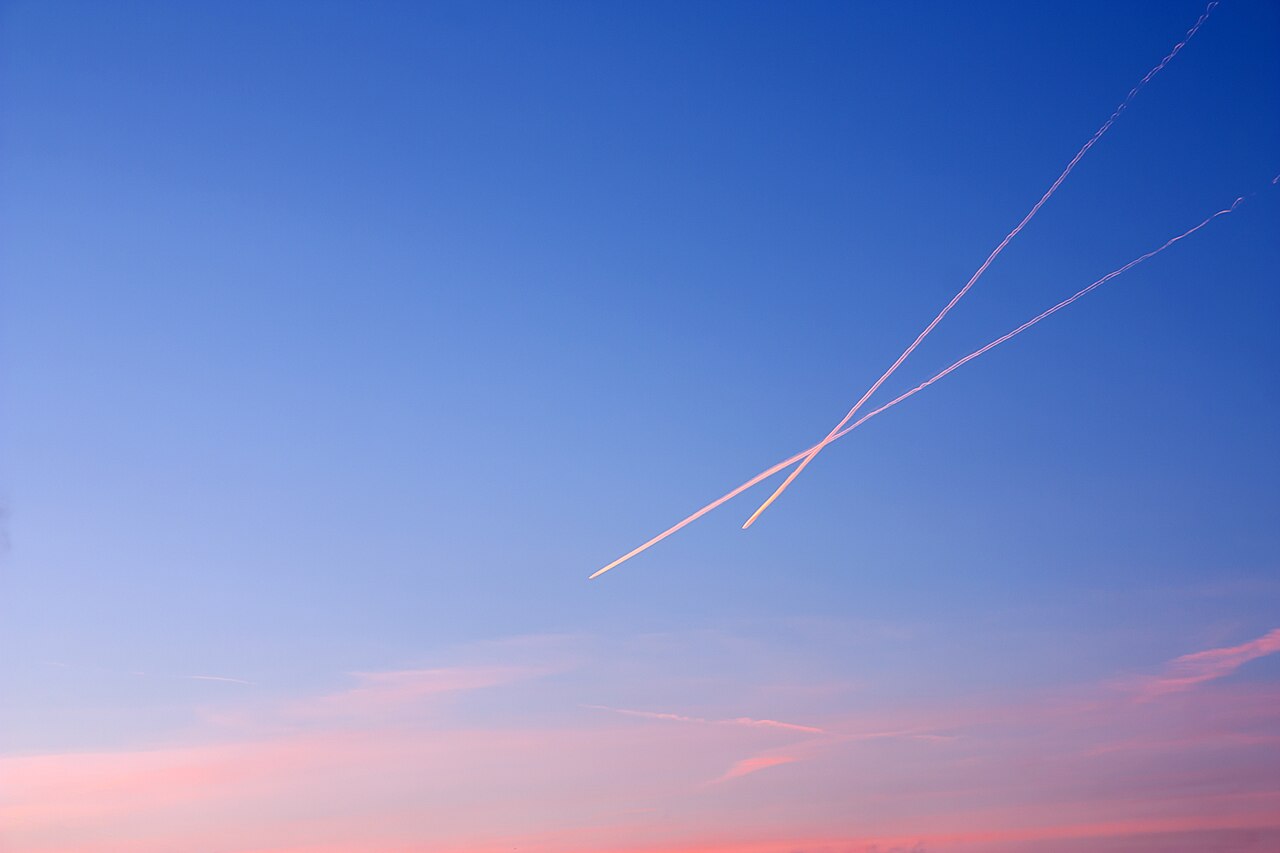 Aircraft contrails crossing the sky at sunset.