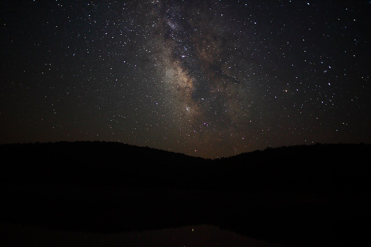 The Milky Way above the silhouette of rolling hills.